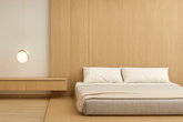 A modern, minimalist bedroom with decorative wall panel, light wood paneling and flooring. The bed has a low, upholstered gray frame with white pillows and a beige blanket.